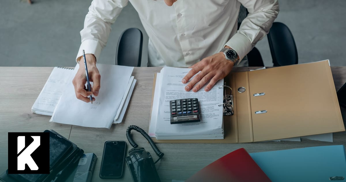 Homme au bureau révisant des documents et une calculatrice — AI Act entreprise 2026, obligations à vérifier pour les TPE/PME
