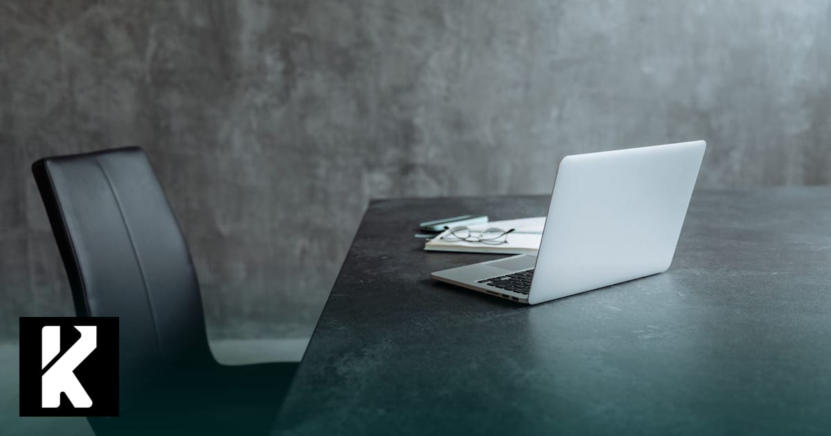 Ordinateur portable ouvert sur un bureau sombre près d'une chaise vide — poste de travail pour une formation IA générative certifiante (RS6776 ou RS7232)