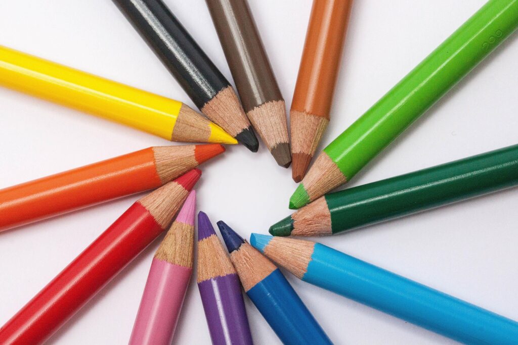 Crayons de couleur disposés en cercle sur fond blanc, symbolisant la diversité des compétences et la créativité en formation – KLEBERT Consulting